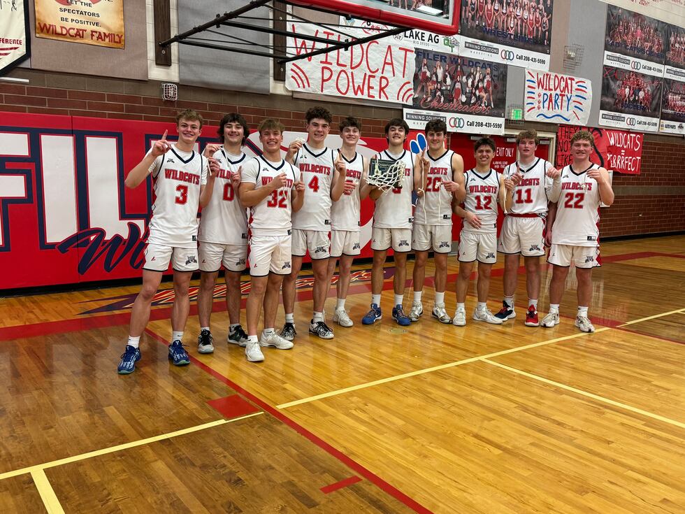 The Filer boys basketball team celebrate with the trophy after beating Kimberly in the 4A SCIC...